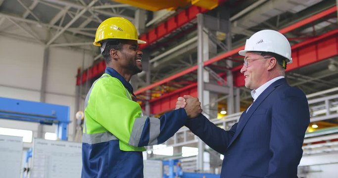 Engineer and foreman give shandshake and hifh five to each other. Good teamwork corporate at heavy industry factory