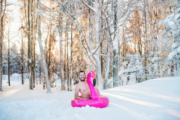 Topless young man outdoors in snow in winter forest, having fun.