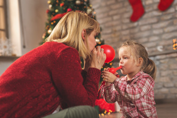 Mother and daughter blowing balloons on Christmas day