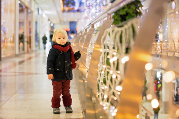 Fashion toddler boy in the city center shopping mall on Christmas