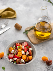 salad with fresh tomatoes, feta cheese, basil, olive oil. Healthy food diet. gray concrete background, vertical image