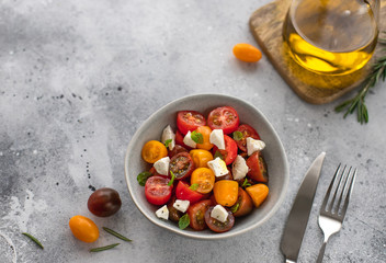 salad with fresh tomatoes, feta cheese, basil, olive oil. Healthy snack concept. gray concrete background, copy space, top view