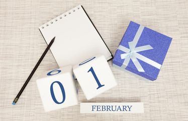 Calendar with trendy blue text and numbers for February 1 and a gift in a box.