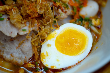 Spicy tom yum noodle with pork and meat ball and egg.