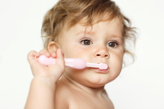 Adorable one year old child learning to brush teeth, isolated on white
