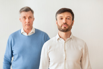 Fototapeta na wymiar Middle-Aged Son And Elderly Father Standing On White Background