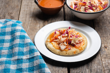 Salvadoran pupusas with coleslaw and tomato sauce on wooden background