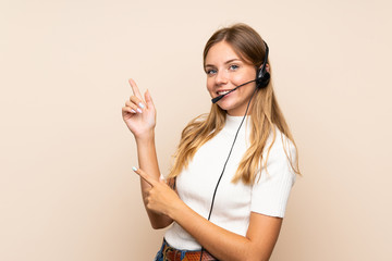 Young blonde woman over isolated background pointing side