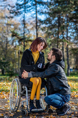 Fototapeta na wymiar Young disabled woman in a wheelchair with boyfriend. Man with disabled girl in a wheelchair