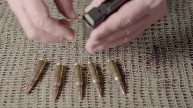 The shooter equips the rifle magazine with 308 caliber ammunition. Close up