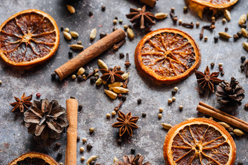 Fototapeta na wymiar Christmas spice background. Cinnamon, cloves, pepper, dried oranges and anise on a grey background.