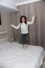 Fototapeta na wymiar Little girl wear long sleeve white shirt.She happy for jumping the bed 