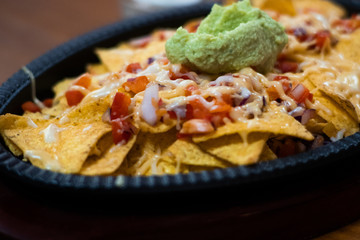 Single frying pan of yellow tortilla chips topped with melted cheese with copy space