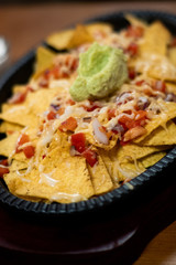 Single frying pan of yellow tortilla chips topped with melted cheese with copy space