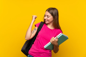 Young student girl over isolated yellow background celebrating a victory