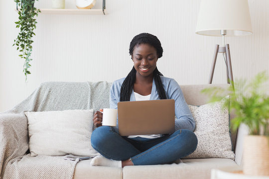 Young afro girl working with laptop on couch at home