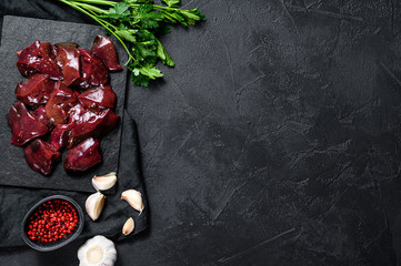 Raw Turkey liver on a stone Board. Black background. Top view. Space for text