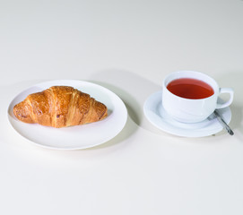 Fruit tea and delicious fresh croissant on the table in a cozy coffee shop