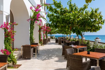 Fotobehang Outdoor restaurant with pink flower bushes on the walls surrounded by trees and sea in Zanzibar © Andy Troy/Wirestock