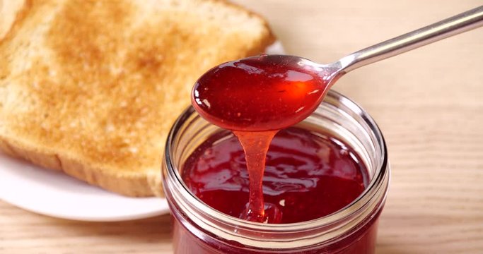 Delicious strawberry jam in glass jar, closeup