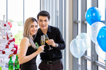 Attractive young couple celebrate Christmas and New Year in party, clinking champagne glass, with snack and beverage on table