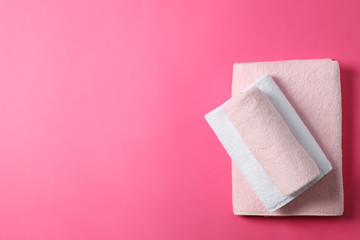 Folded towels on pink background, top view and space for text