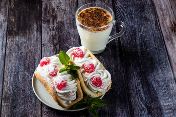 Air cake with raspberries on a saucer. Kefir with cinnamon, fermented drink. wood background