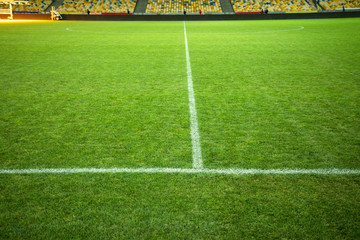 Football field with green grass and marking. Soccer field. White line markings on the field. Places for the audience in the distance. © Kozachenko Oleksandr