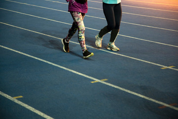 Fototapeta premium Runners at the stadium. Athletes are involved in athletics. Treadmills with markings. Legs of running people. Two athletes are running on the stadium.