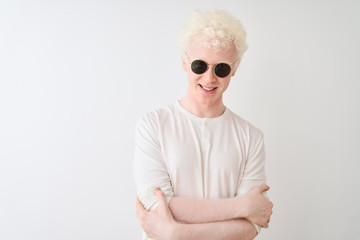 Young albino blond man wearing t-shirt and sunglasses over isolated white background happy face smiling with crossed arms looking at the camera. Positive person.