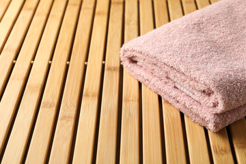 Folded pink towel on bamboo background, close up and space for text