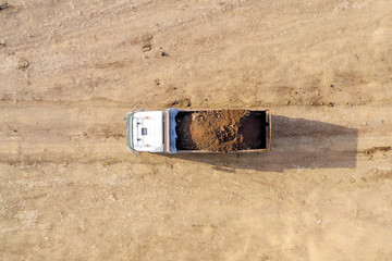 Large Truck hauling a full load of Excavated Soil on a dirt road, Top down aerial.