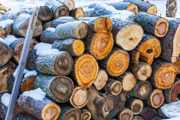 Stacked wood covered with snow. Background. A woodpile of dry fire woods in the winter. Stack of fire wood with snow. Winter fire wood provisions. Row of fire wood stock for winter. Winter.