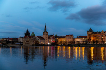 Fototapeta na wymiar The center of Prague Czech Republic and its biggest landmark on the Vltava river Charles Bridge and the beautiful waterfront illuminated during Christmas at sunset with reflections
