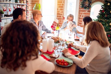 Family and friends dining at home celebrating christmas eve with traditional food and decoration, celebration of festive winter time