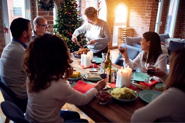 Family and friends dining at home celebrating christmas eve with traditional food and decoration, preparing turkey for dinner