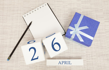 Calendar with trendy blue text and numbers for April 26 and a gift in a box.