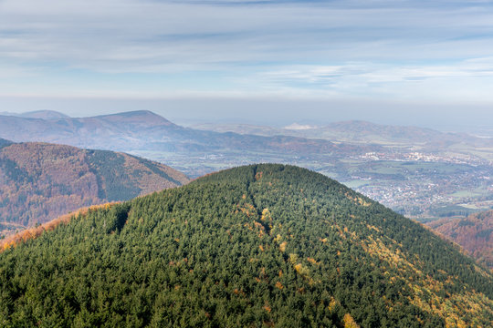 Hills and mountains on the horizon of beautiful nature with city in the forest valley view into vast distance of the Beskids Area during a windy sunny day captured in Radhost Pustevny area