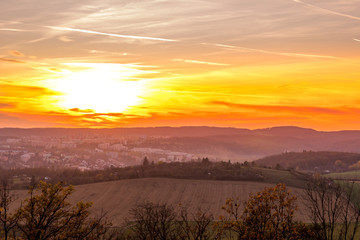 Sunset overlooking nature and landscape from Brno hill sunset couple of moments before sunset orange color with clouds moving in the background and planes flying in the sky.