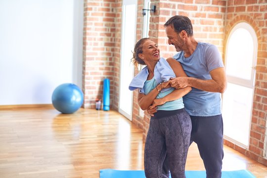 Middle age beautiful sporty couple smiling happy. Standing with smile on face hugging at gym