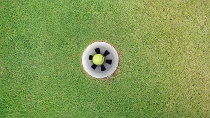 Yellow ball getting into a hole on a golf course.