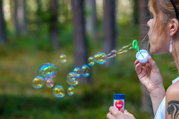 young woman blowing bubble in forest