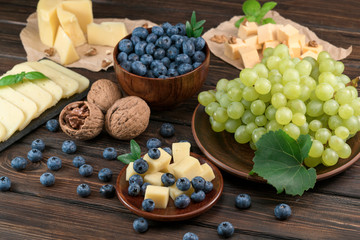 cheese, blueberries and grapes on a wooden background
