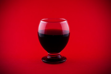 Glass of red wine on red background