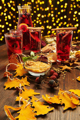 Christmas mulled wine or gluhwein with spices, chocolate candies, sweets and orange slices on rustic table, traditional drink on winter holiday, christmas lights and decorations