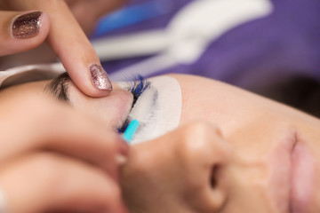 Woman on a cosmetic procedure for eyelash extension. Face close up.