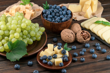 cheese, blueberries and grapes on a wooden background