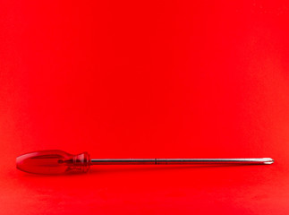 Red screwdriver on red background with copy-space
