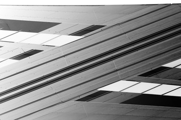 Low angle view of gray steel wall panels with slots. Fragment of industrial building exterior. Abstract modern architecture background with geometric structure. Parallel lines in diagonal composition.