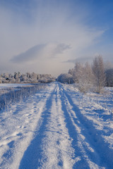 Fototapeta na wymiar car tracks in the snow on the winter road in sunny day